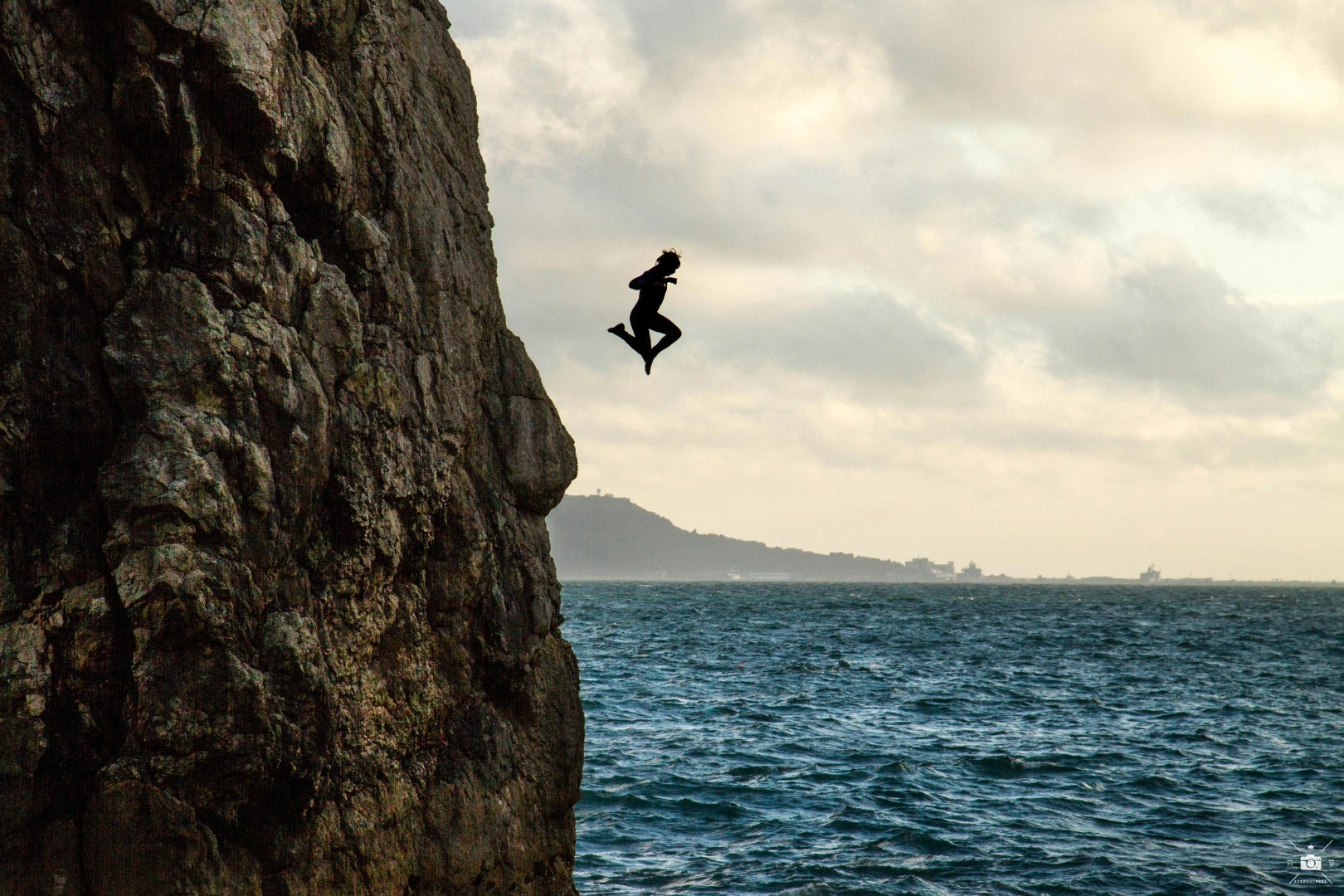 Person diving off a cliff into the open sea